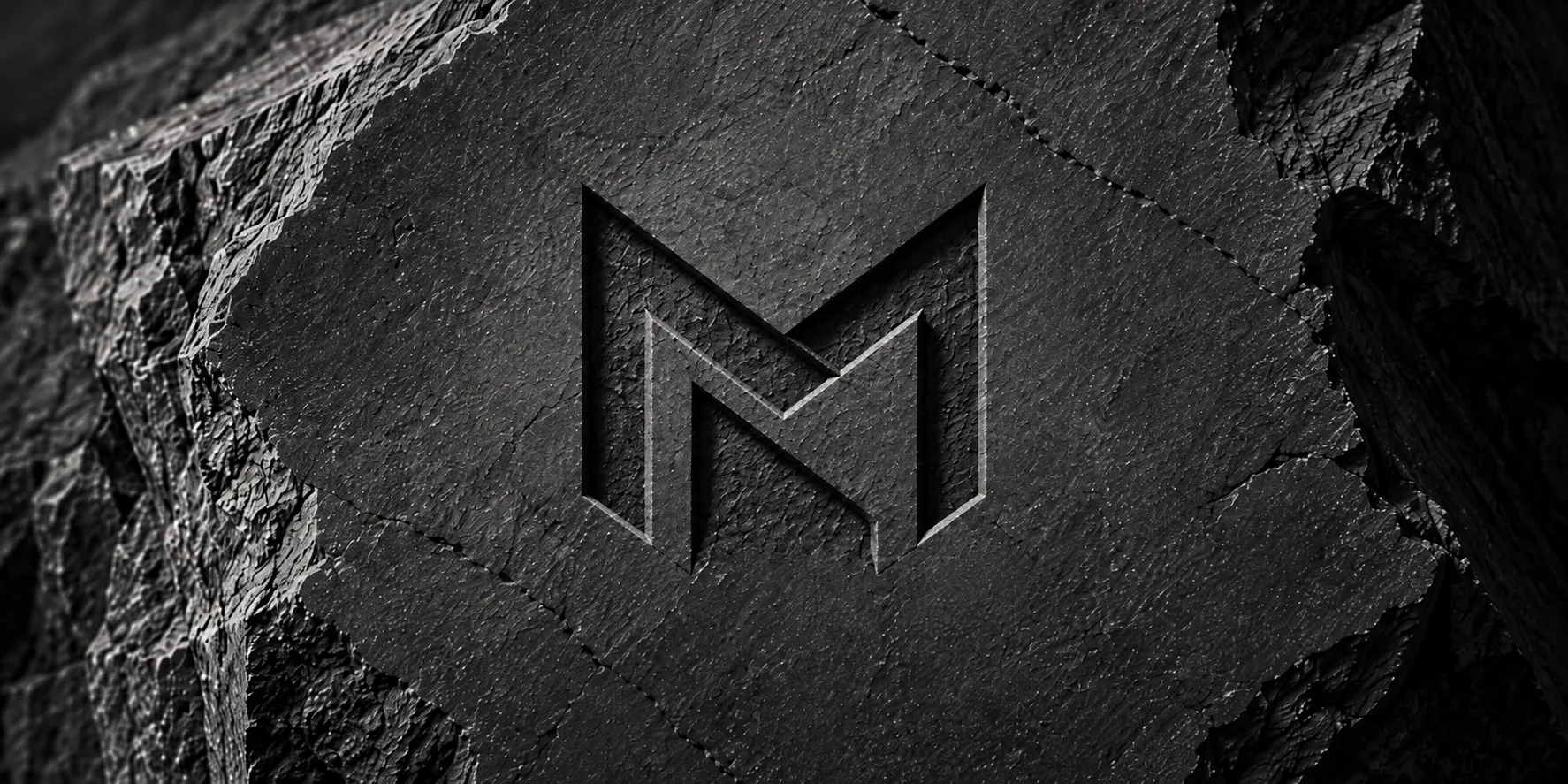 Koyu taş yüzeye oyulmuş M harfli logo